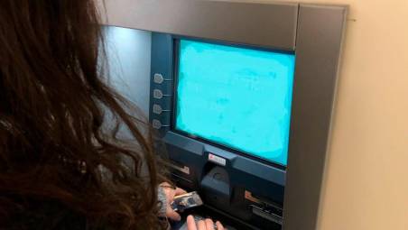Una ragazza mentre effettua un prelievo al bancomat