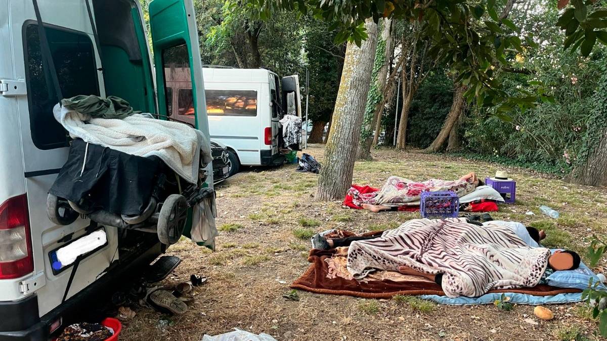 Gente che dorme sull’erba di un parcheggio