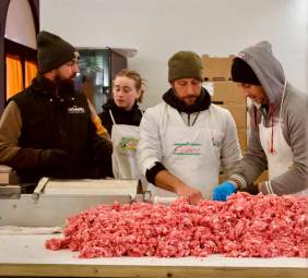 Volontari al lavoro per preparare la carne di maiale