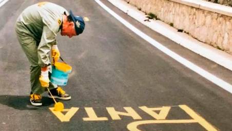 Bianco impegnato a scrivere su una strada il nome di Pantani