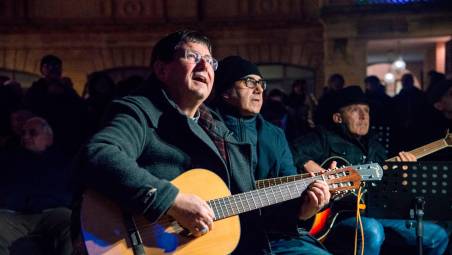 I partecipanti all’evento assieme al vescovo Anselmi e i testi delle canzoni proiettati sul Duomo (Morosetti)