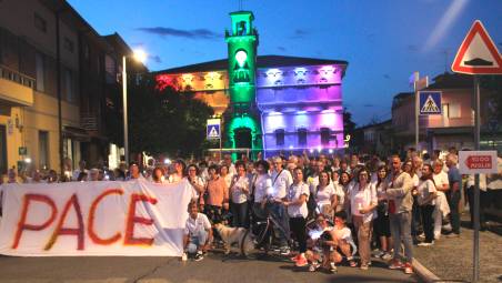 In posa con il sudario di pace davanti al municipio illuminato con i colori della bandiera della pace