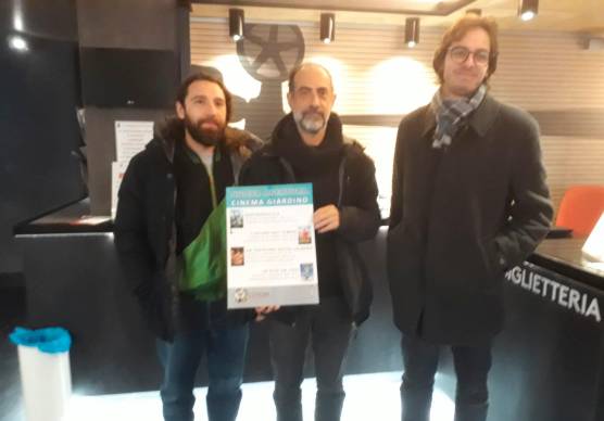 Don Marco Ferrini, al centro, mostra il primo cartellone insieme a due membri dello staff