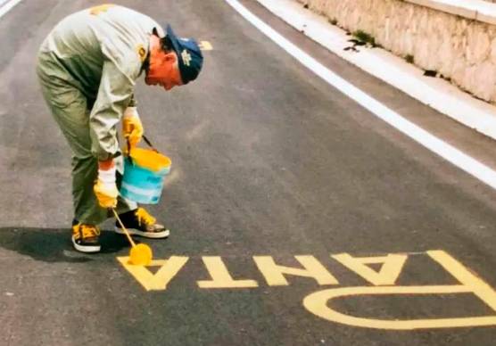 Bianco impegnato a scrivere su una strada il nome di Pantani