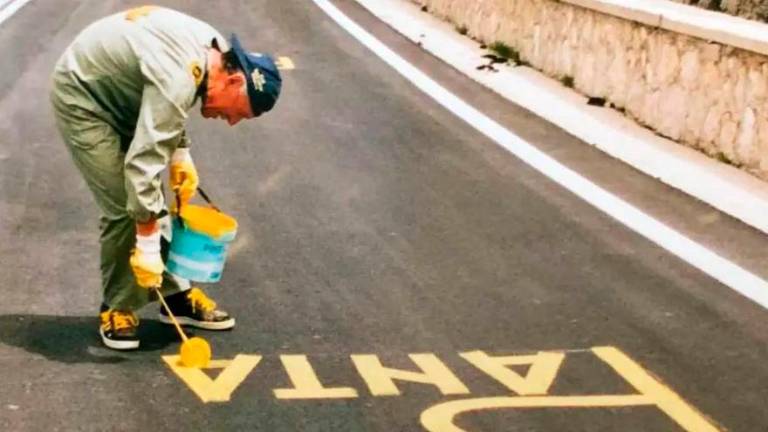 Bianco impegnato a scrivere su una strada il nome di Pantani