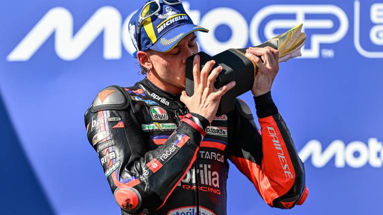 In alto la festa di Bezzecchi con il box Aprilia al completo, sopra quella sul podio