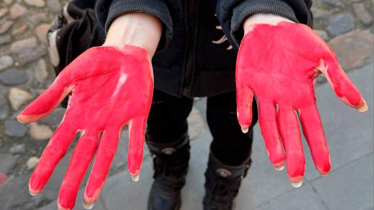 Le mani tinte di rosso di alcune donne in piazza del Popolo