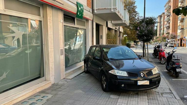 Parcheggia senza il freno a mano in discesa: l'auto si schianta sulla vetrata della Bnl a Cesena