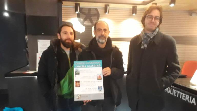 Don Marco Ferrini, al centro, mostra il primo cartellone insieme a due membri dello staff