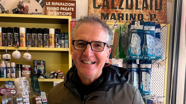 Maurizio Scarponi nel suo negozio, alle spalle l’insegna storica del suo maestro